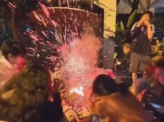 Fogueira explode, banhando o grupo com faíscas e carvão quente