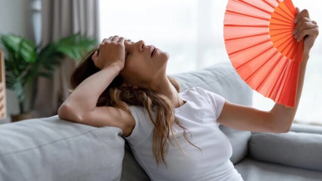 overheated-woman-with-hand-fan-on-couch.jpg